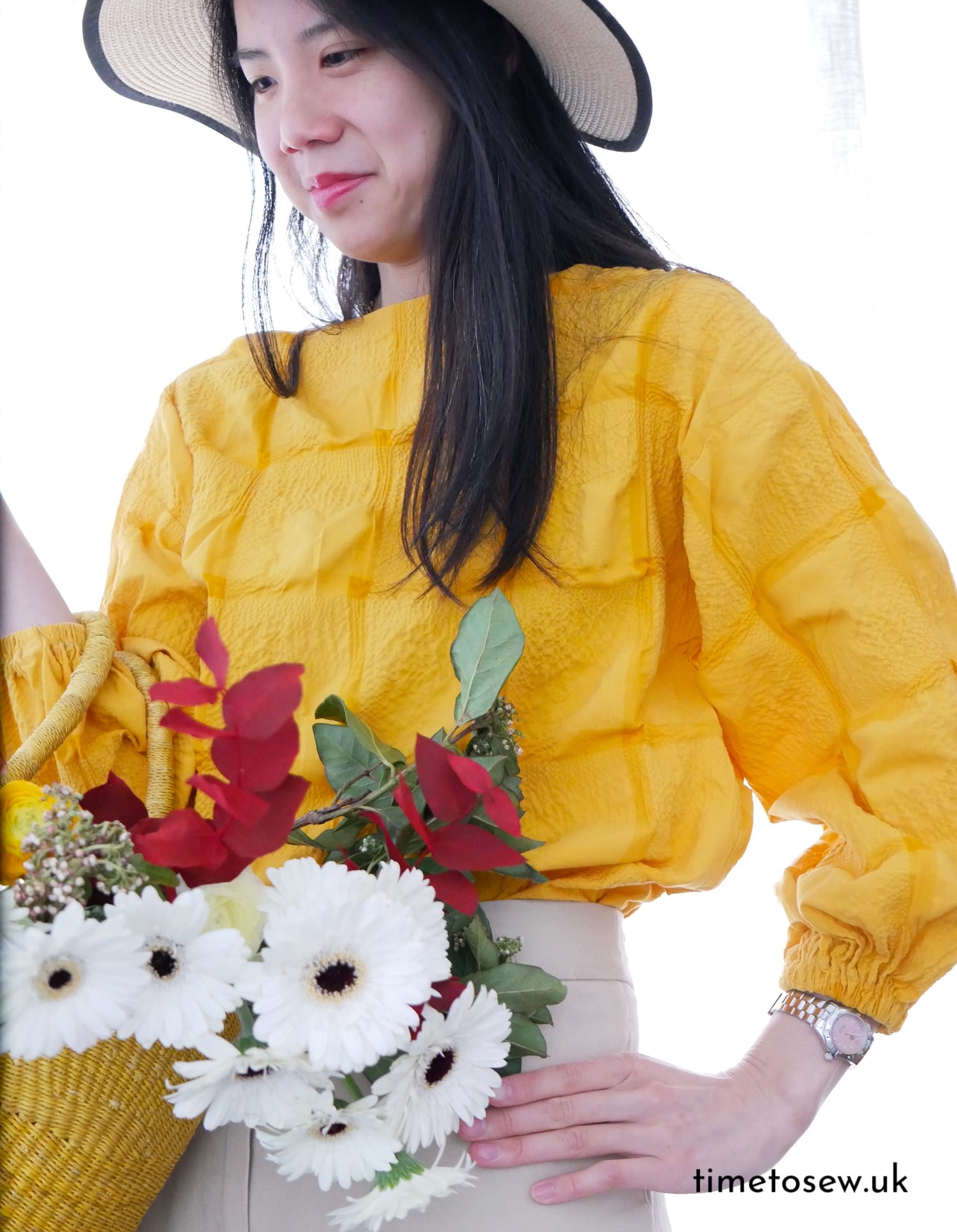 Kate wears a yellow top (Just Patterns Tyra tee) with an XL grid pattern with a summer hat and a basket of flowers